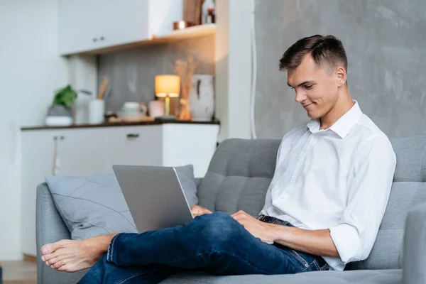 Jovem está trabalhando em um laptop na sala de estar. — Fotografia de Stock