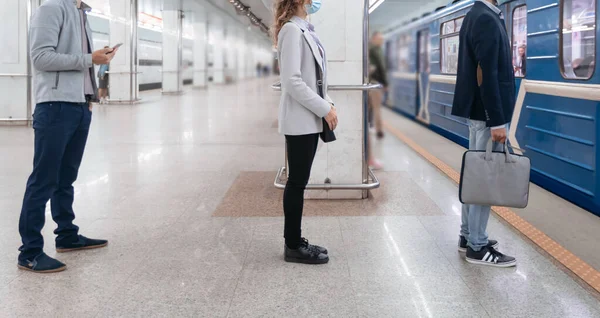 Menschen in Schutzmasken warten auf dem U-Bahnsteig auf den Zug . — Stockfoto