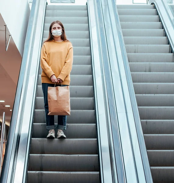 Mulher solitária em uma máscara protetora em pé nos degraus escada rolante — Fotografia de Stock