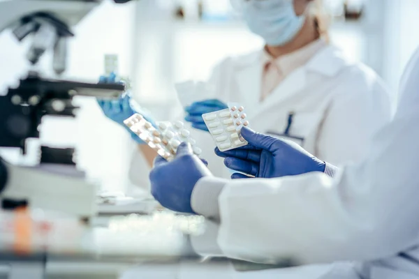 Cientistas com amostras de novas drogas sentadas em uma mesa de laboratório. — Fotografia de Stock