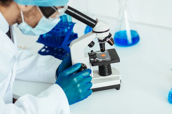 Wetenschapper die een controlesteekproef door een microscoop bekijkt. — Stockfoto