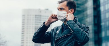 Sokakta duran koruyucu bir maske takan genç adam.