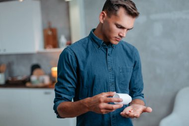 Grip olmuş genç bir adam evde ilaç alıyor..