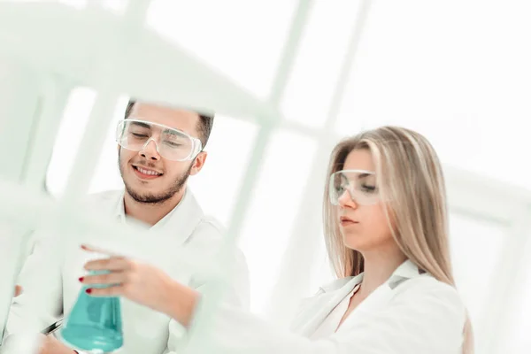 Leende vetenskapsman visar sin kollega en flaska vätska. — Stockfoto