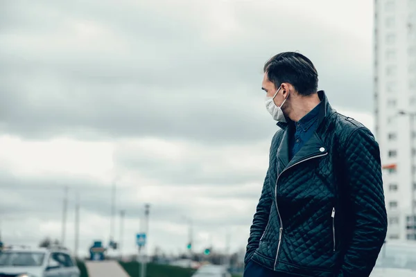 Man met een beschermend masker kijkt naar de lege straat — Stockfoto