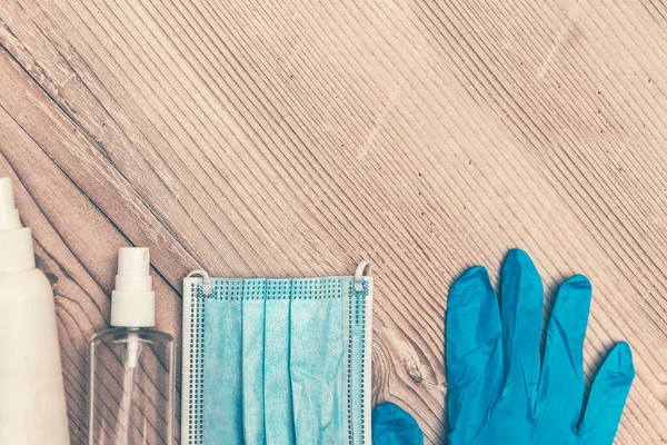 Desinfectante líquido, spray, mascarilla protectora y guantes en una mesa de madera — Foto de Stock