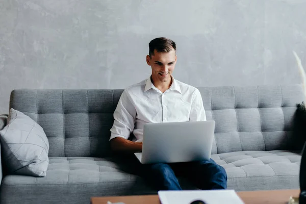 Jovem empreendedor trabalha em um laptop em seu apartamento . — Fotografia de Stock