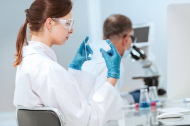 Kadın bilim adamı laboratuarda koruyucu bir maske takıyor..