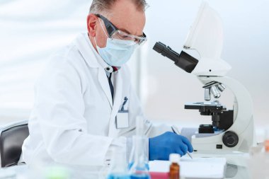 Kapat. Koruyucu maskeli bilim adamı laboratuvarda araştırma yapıyor..