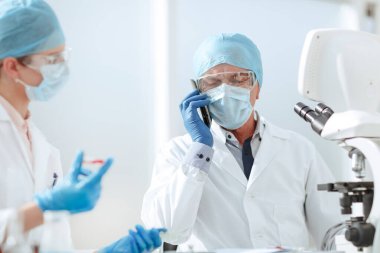 Kapat. Laboratuvarda cep telefonuyla konuşan bir bilim adamı..