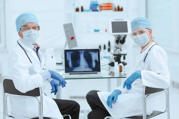 På nära håll. medicinska kollegor som sitter vid ett bord i laboratoriet . — Stockfoto