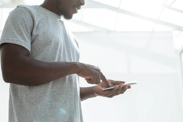 close up. smiling guy choosing a contact on his smartphone