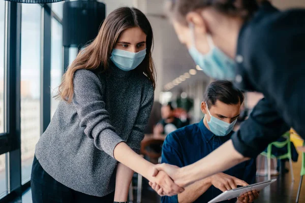 Jong personeel in beschermende maskers schudden handen met elkaar. — Stockfoto