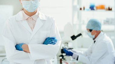 Kapat. Laboratuvarda duran koruyucu maskeli bir doktor..