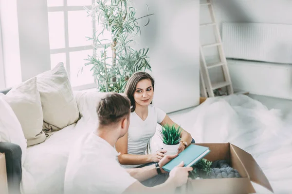 Pareja abriendo una caja de cartón en un apartamento nuevo . — Foto de Stock