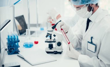 Kapat. Bilim adamı yeni bir test numunesi içeren bir tüp tutuyor..
