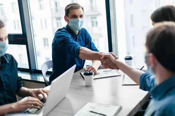 Jonge zakenpartners in beschermende maskers schudden handen met elkaar. — Stockfoto