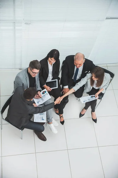 Vista superior. colegas de negocios estrechando la mano en una reunión de oficina . — Foto de Stock