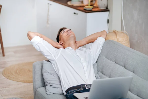 Ung man med en laptop är avkopplande i vardagsrummet . — Stockfoto