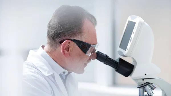 De cerca. científico mirando cuidadosamente a través de un microscopio. — Foto de Stock