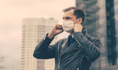 Sokakta duran koruyucu bir maske takan genç adam.