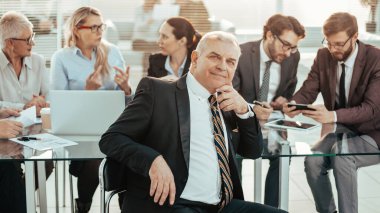 Ofis masasının önünde oturan başarılı bir iş adamı.