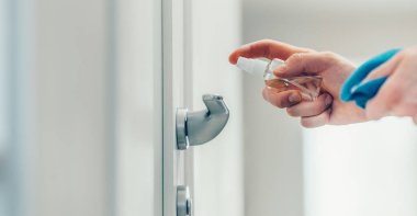 Kapat. Adam kapı koluna antiseptik püskürtüyor..