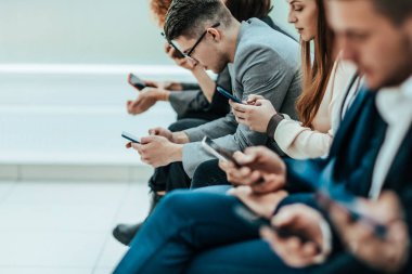 Sıraya dizilmiş akıllı telefonları olan bir grup genç.