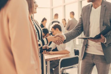 Kapat. Yönetici genç bir iş kadınının elini sıkıyor.