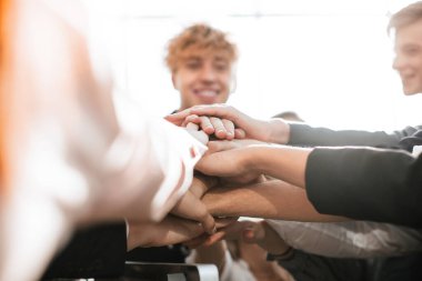 Bir grup genç insan avuçlarını birleştiriyor.