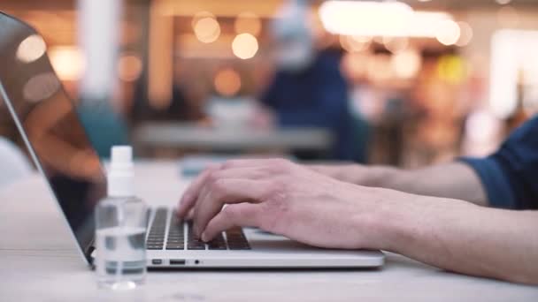 Jeune homme travaille à taper un message sur un ordinateur portable alors qu'il est assis dans un café. gros plan . — Video
