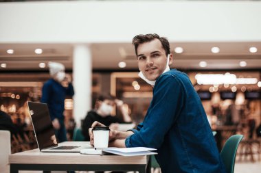 Bir kafede masada oturan düşünceli genç adam.