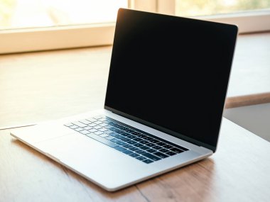 Kapat. Tahta bir masada dizüstü bilgisayarı aç.