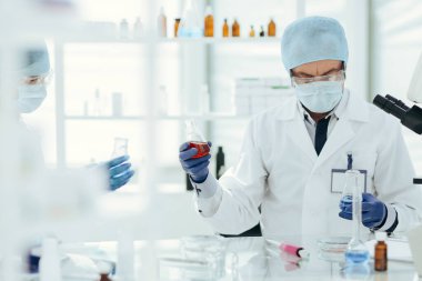 Bilim adamları laboratuvar mataralarında sıvıyı kontrol ediyorlar..