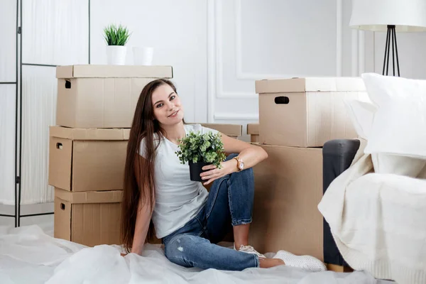 Mladá žena s domácí rostlina sedí na podlaze v novém l — Stock fotografie