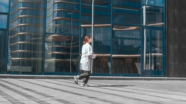 Ενδιαφερόμενο γιατρό γυναίκα τρέχει κοντά σε ένα κτίριο της πόλης. — Φωτογραφία Αρχείου