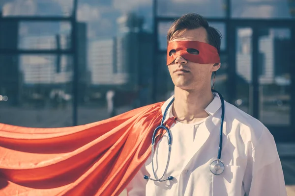 doctor hero in a Superman Cape standing on a city street.