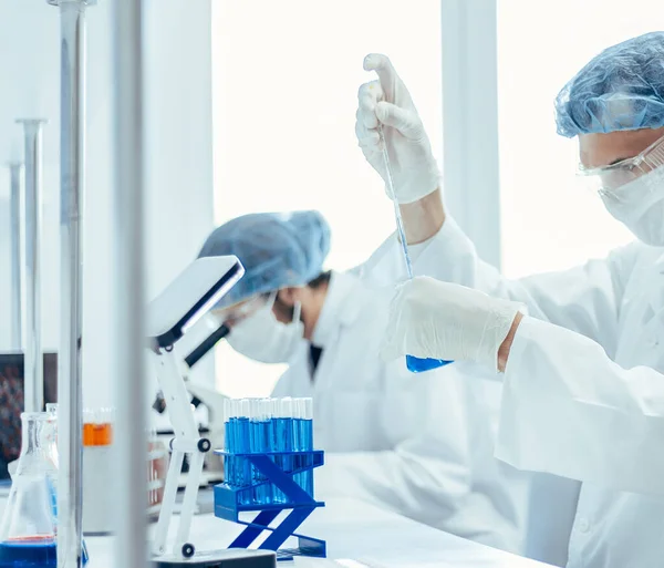 Fecha. garrafa de líquido azul nas mãos de um cientista. — Fotografia de Stock