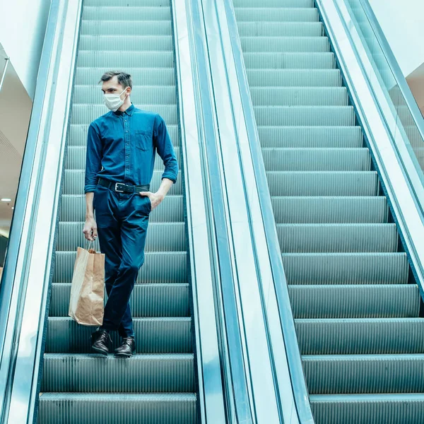 Homme seul dans un masque de protection debout sur les marches de l'escalator — Photo