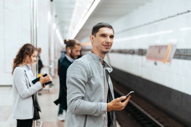 Genç adam metro istasyonunda tren bekliyor..