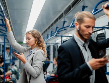 Metro vagonunda akıllı telefonlarını kullanan yolcular .