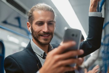 Metroda akıllı telefonunu kullanan çekici bir adam. .