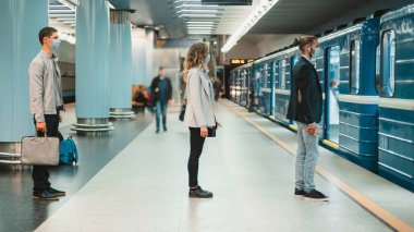 Metro platformunda duran koruyucu maskeli insanlar. .