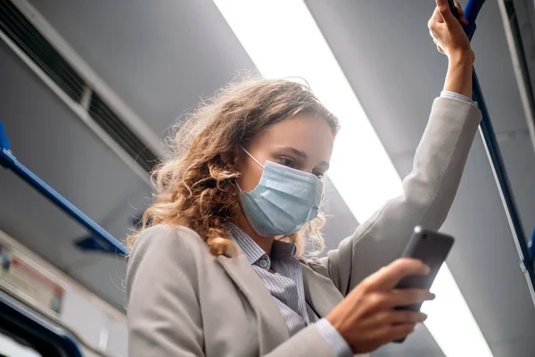 Jovem mulher em uma máscara protetora em pé em um trem de metrô. — Fotografia de Stock