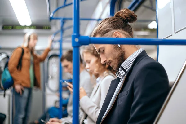 tired business man sleeps in a subway train car.