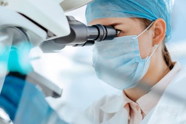 Kadın bilim adamı bir tıp laboratuarında mikroskop kullanıyor..