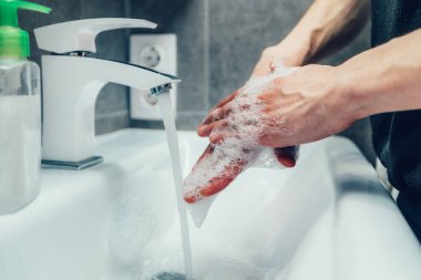 Kapat. Ellerini banyoda sabunluyor..