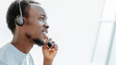 Yan görünüş. Kulaklıklı genç adam mikrofona konuşuyor.