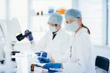 Bilim adamları sıvıyı test ediyor ve sonuçları laboratuvar dergisine yazıyorlar..