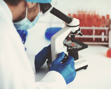 Bilim adamı mikroskopla kontrol örneğine bakıyor..